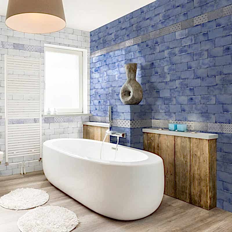 Vita Blue Brick Tiles on a bathroom wall/ Rounded white bathtub in front of wwoden panels.