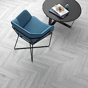 Ebony Grey Herringbone Tiles in a room setting with a blue armchair and small round black table
