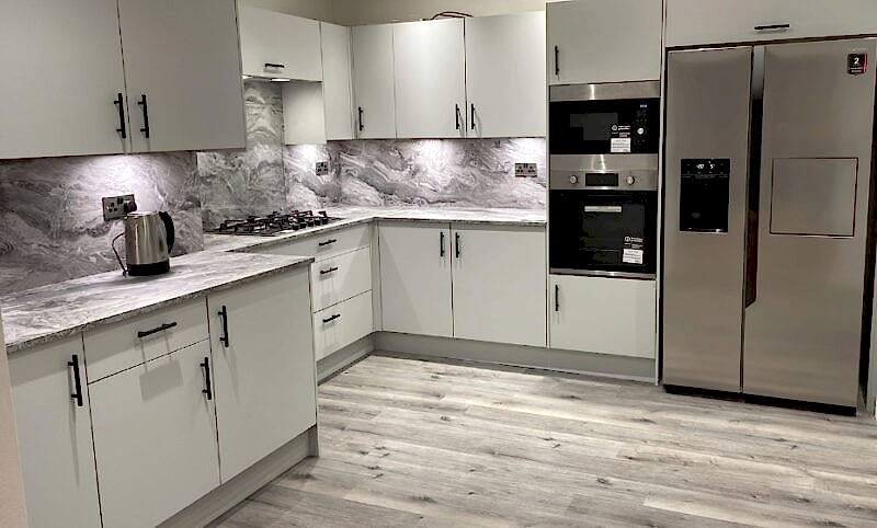 Room shot of Jean's Grey Kitchen after renovation showing grey vinyl flooring and marble splashback above the counters