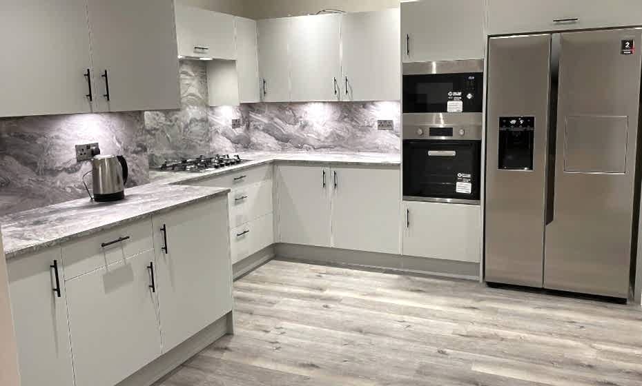 Room shot of Jean's Grey Kitchen after renovation showing grey vinyl flooring and marble splashback above the counters