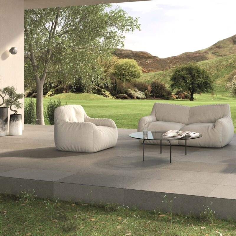 Juliette Pale Grey Stone Effect Tiles in an outdoor setting wiht patio furniture and scenic views