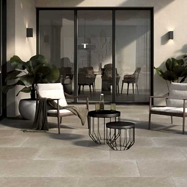Taxos Light Grey Limestone Tiles in a patio setting. French windows in the background and patio furniture.
