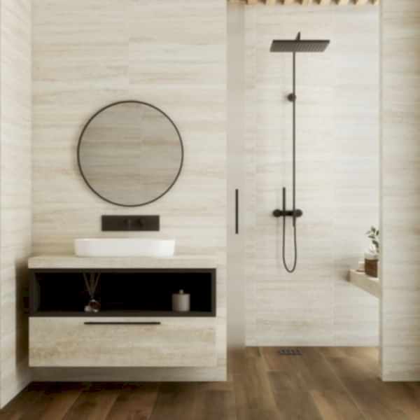 Versilia Travertine Tiles - Cream in a bathroom setting with a unti and round mirror to the left, shower to the right